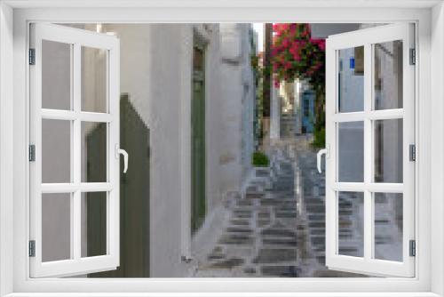 Fototapeta Naklejka Na Ścianę Okno 3D - Traditional Cycladitic alley with a narrow street, whitewashed houses and a blooming bougainvillea in Parikia, Paros island, Greece