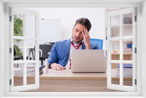 Young male employee suffering at workplace