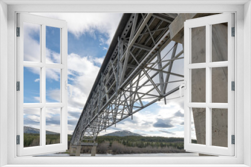 Fototapeta Naklejka Na Ścianę Okno 3D - Large steel structure bridge in northern Canada in artistic style with blue sky clouds in the background. Taken from underneath the magnificent transport bridge. 