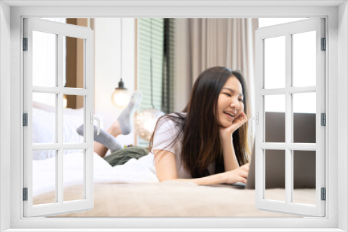 happy Young asian woman  working with laptop in bed at home in the morning. lifestyle concept