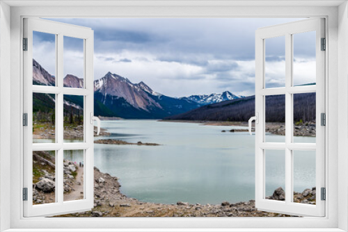Fototapeta Naklejka Na Ścianę Okno 3D - Medicine Lake in Jasper National Park in the Canadian Rockies under Dark Clouds. The lake fills and empties annually as the water drains through an underground drainage system