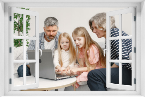 Grandarents with granddaughters using laptop in the living room