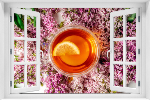 Fototapeta Naklejka Na Ścianę Okno 3D - A mug of tea with lemon and lilac. Cozy romantic floral background with copy space. Flat lay.
