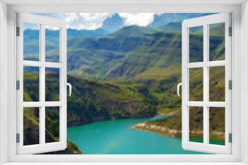 Fototapeta Naklejka Na Ścianę Okno 3D - Vertical mountain landscape view with a lake on a summer sunny day. Scene with high hills, body of turquoise water and background of blue sky with white clouds.