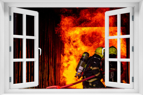 Fototapeta Naklejka Na Ścianę Okno 3D - firefighters wearing fire fighter suit for safety and using twirl water extinguisher for fighting the fire flame in emergency situation.. - Safety Firefighter and industrial concept.