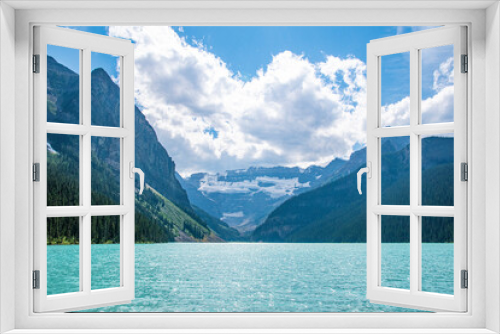 Fototapeta Naklejka Na Ścianę Okno 3D - The glacial waters of Lake Louise bask in the bright sunlight, surrounded by the Canadian Rocky Mountains in Banff National Park, Alberta.