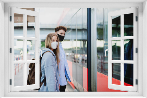 Young couple tourist travelers on holiday at the bus stop in city, coronavirus concept.