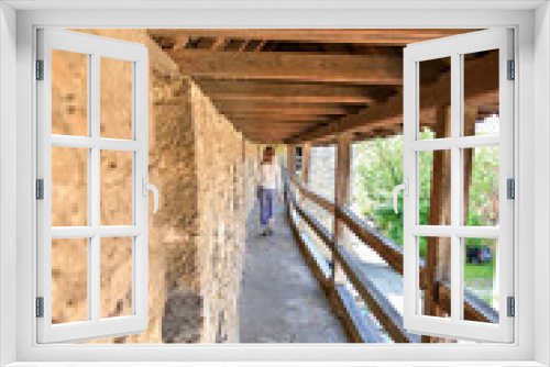 Fototapeta Naklejka Na Ścianę Okno 3D - Junge Frau läuft den den Laubengang Stadtmauer Rothenburg ob der Tauber
