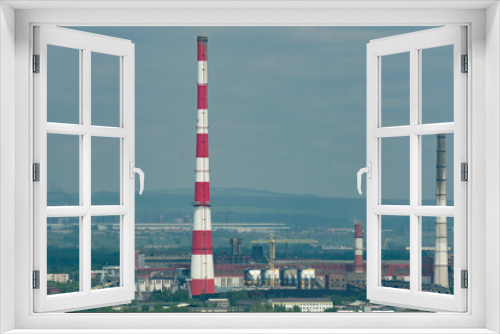 Fototapeta Naklejka Na Ścianę Okno 3D - A huge red-white brick chimney in the center of an industrial city.