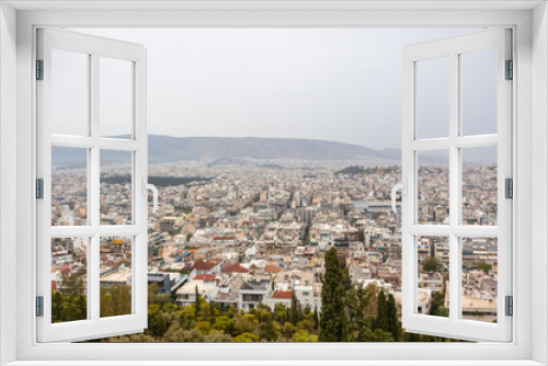 Fototapeta Naklejka Na Ścianę Okno 3D - Athens city center streets with white architecture, mountain silhouette and greenery on gray foggy day. Rooftop view from Filopappou Hill park near Acropolis, Greece