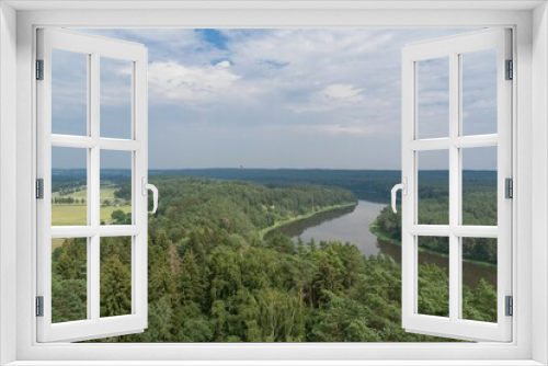 Fototapeta Naklejka Na Ścianę Okno 3D - Panoramic view from the top of Merkine observation tower onto Nemunas river and surrounding riverbanks covered with green forest. Warm summer day. White clouds in blue sky.
