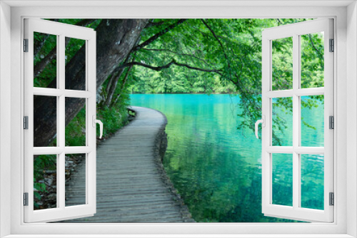 Fototapeta Naklejka Na Ścianę Okno 3D - Scenic empty walkway runs along the shore of emerald lake in Plitvice park.