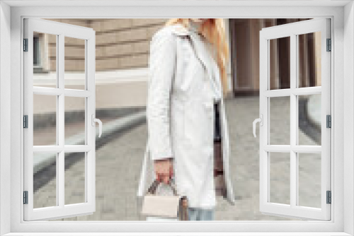 Young fashion blonde woman in a trench coat with bag in city