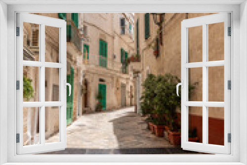 Fototapeta Naklejka Na Ścianę Okno 3D - malownicza uliczka białych kamienic z zielonymi okiennicami. Monopoli, Puglia, Włochy