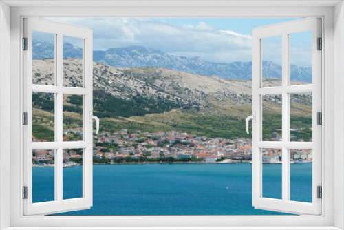 Fototapeta Naklejka Na Ścianę Okno 3D - View over blue adriatic sea on village with dizzy mountains background - Island Pag, Croatia (focus on center of village)