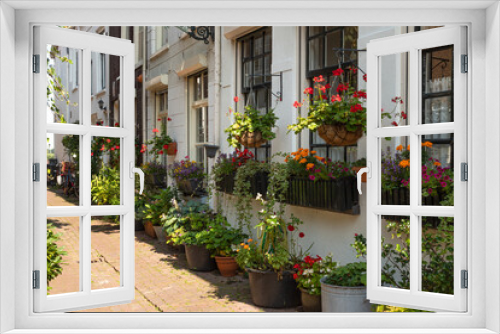 Fototapeta Naklejka Na Ścianę Okno 3D - A narrow street with colorful flowering plants in flower pots in the picturesque town of Kampen in the province of Overijssel.