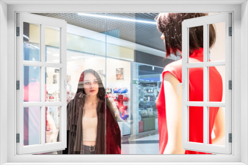 A beautiful girl looks at a shop window in a shopping center.