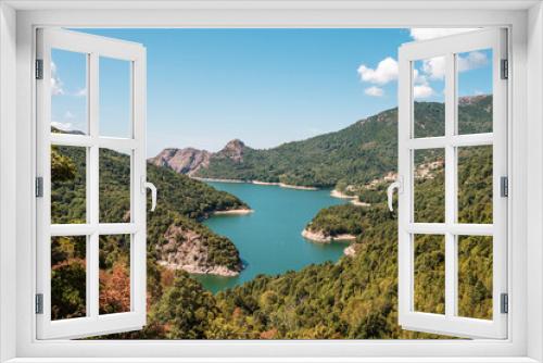 Fototapeta Naklejka Na Ścianę Okno 3D - The dam wall at Lac de Tolla in Corsica surrounded by rocky cliffs and pine forest with mountains in the distance