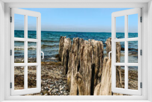 Fototapeta Naklejka Na Ścianę Okno 3D - Alte Holzpfähle am Strand direkt ins blaue Meer übergehend