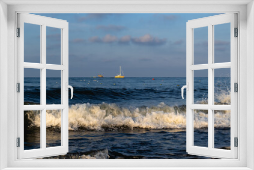 Fototapeta Naklejka Na Ścianę Okno 3D - A seascape overlooking a sea foam wave that rolls ashore and a lonely boat far on the horizon.