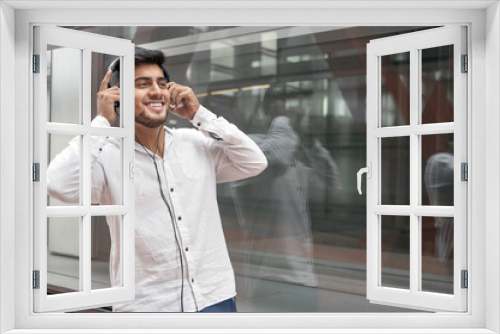 Handsome young man smiling and listening music on the street. High quality photo