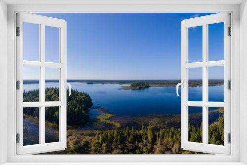 Fototapeta Naklejka Na Ścianę Okno 3D - Aerial panorama of a large dark blue lake that is surrounded by trees. The sun is in the photo.
