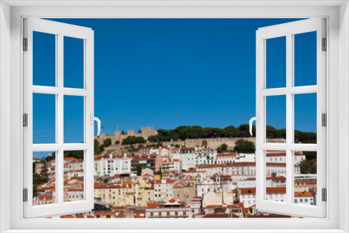 Fototapeta Naklejka Na Ścianę Okno 3D - Lisbon St George Castle on top of the hill with houses below and blue sky