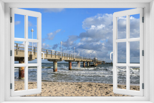 Fototapeta Naklejka Na Ścianę Okno 3D - Seabridge at the beach in the tourist resort zinnowitz at the baltic sea, windy weather with waves on the water and blue sky with clouds, copy space