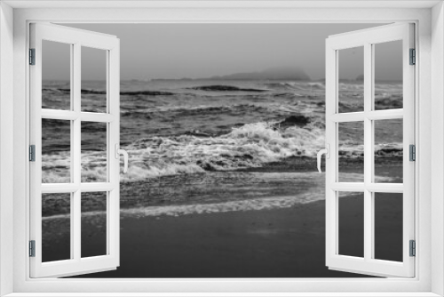 Fototapeta Naklejka Na Ścianę Okno 3D - Panoramic view of the shore, the pacific ocean with waves, the horizon with cloudy sky and beach (in black and white)