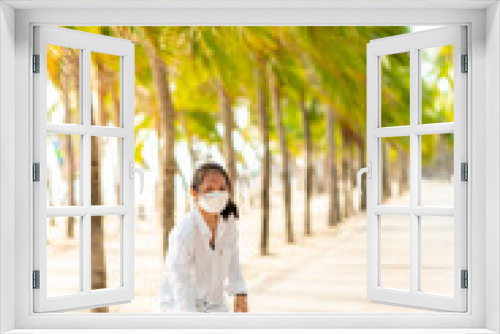 Teen Asian girl in white shirt and jeans is practicing for a play. Surf skating along the beachfront promenade behind many coconut trees, Bangsaen, Thailand.