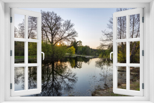 Fototapeta Naklejka Na Ścianę Okno 3D - The river floods in early spring. Picturesque landscape spring evening. Sunbeams at sunset. Reflection of trees in the water.