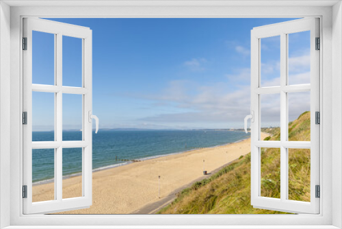 Fototapeta Naklejka Na Ścianę Okno 3D - A scenic majestic view of  Bournemouth bay with sandy beach from a grassy cliff under a beautiful blue sky and some white clouds