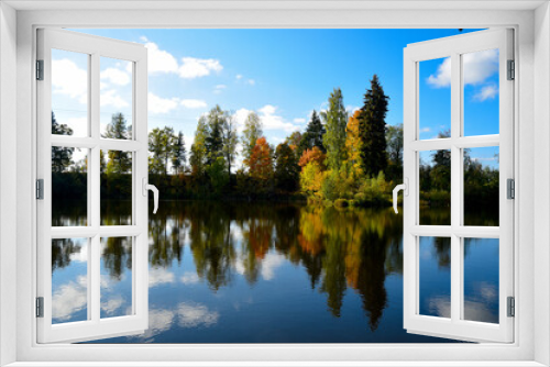 Fototapeta Naklejka Na Ścianę Okno 3D - a beautiful golden autumn reflection in a lake with different colored trees and blue skies