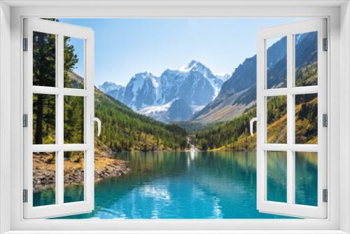 Fototapeta Naklejka Na Ścianę Okno 3D - Amazing clear mountain lake in forest among fir trees in sunshine. Bright scenery with beautiful turquoise lake against the background of snow-capped mountains. Lower Shavlin Lake