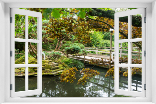 Fototapeta Naklejka Na Ścianę Okno 3D - Japanese garden with a wooden bridge over a pond with coy carp
