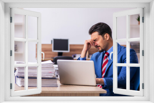 Young male employee unhappy with excessive work at workplace