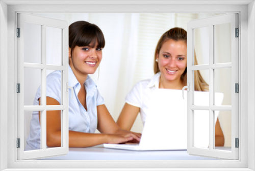 Smiling young businesswomen using laptop together