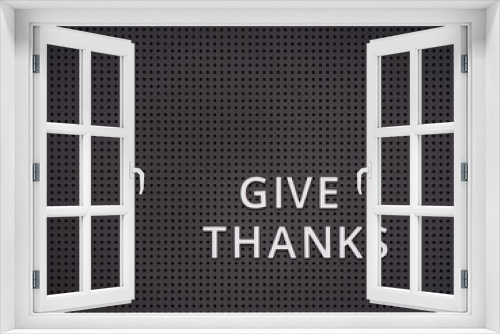 Words Give Thanks spelled out with white letters on gray pegboard.