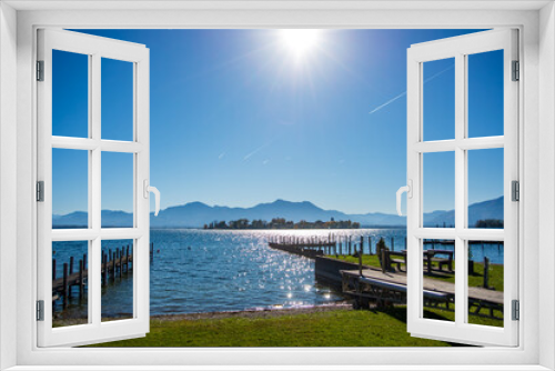 Fototapeta Naklejka Na Ścianę Okno 3D - View of Fraueninsel on lake Chiemsee on a clear autumn morning with the alps in the background and contrails