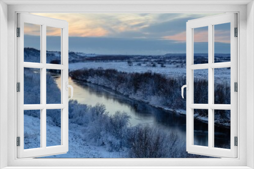 Fototapeta Naklejka Na Ścianę Okno 3D - A beautiful winter view from the hill to the river with frosty trees growing along the banks. Winter landscape at sunset