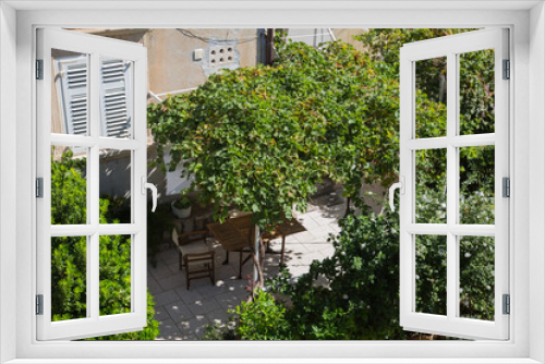 Fototapeta Naklejka Na Ścianę Okno 3D - Garden and terrace design and landscaping: Cozy garden furniture, chairs, table put on a tiled terrace surrounded by lush mediterranean green plants, bushes, palms which dispense shadow, croatia