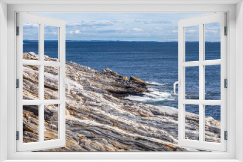 Fototapeta Naklejka Na Ścianę Okno 3D - The flag of the United States of America flies patriotic and proud at the Pemaquid Point Lighthouse on the Atlantic Coast of Down East Maine near Bristol.