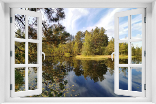 Fototapeta Naklejka Na Ścianę Okno 3D - The mirror surface of a forest lake, in which trees and the sky with beautiful clouds are reflected.
