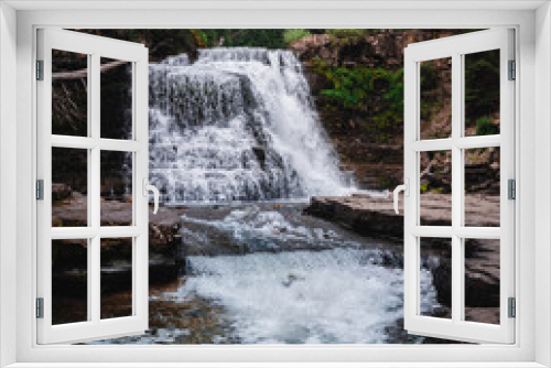Fototapeta Naklejka Na Ścianę Okno 3D - large cascading waterfall surrounded by rocks and trees