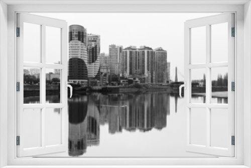 Fototapeta Naklejka Na Ścianę Okno 3D - view of new modern multi-storey apartment buildings with reflection in the water of the Kuban river on a foggy autumn morning black and white photo