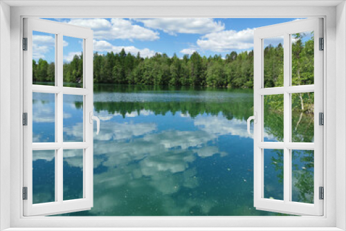 Fototapeta Naklejka Na Ścianę Okno 3D - The shore of the lake is bright with clear water, in which you can see the marble on the bottom and reflect the sky with clouds, in the mountain park Ruskeala.