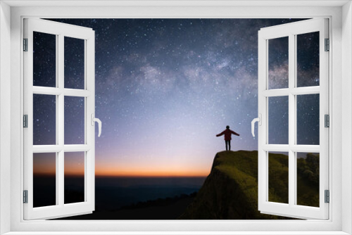 Fototapeta Naklejka Na Ścianę Okno 3D - Silhouette of young traveler and backpacker watched the star, milky way and beautiful view night sky alone on top of the mountain. He enjoyed traveling and was successful when he reached the summit.