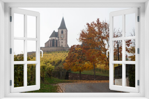 Fototapeta Naklejka Na Ścianę Okno 3D - view of beautiful autumnal landscape with maple trees and medieval church in the vineyard by foggy day