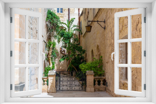 Fototapeta Naklejka Na Ścianę Okno 3D - Lush green plants surrounded by limestone walls of Mdina town, Malta.