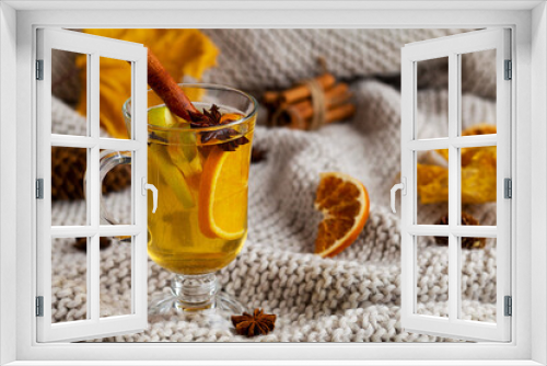 Fototapeta Naklejka Na Ścianę Okno 3D - Mulled drink on knitting plaid with copy space. Christmas hot white mulled wine in glass with orange, honey, cinnamon sticks and star anise dry leaves on light background. Spicy warm beverage
